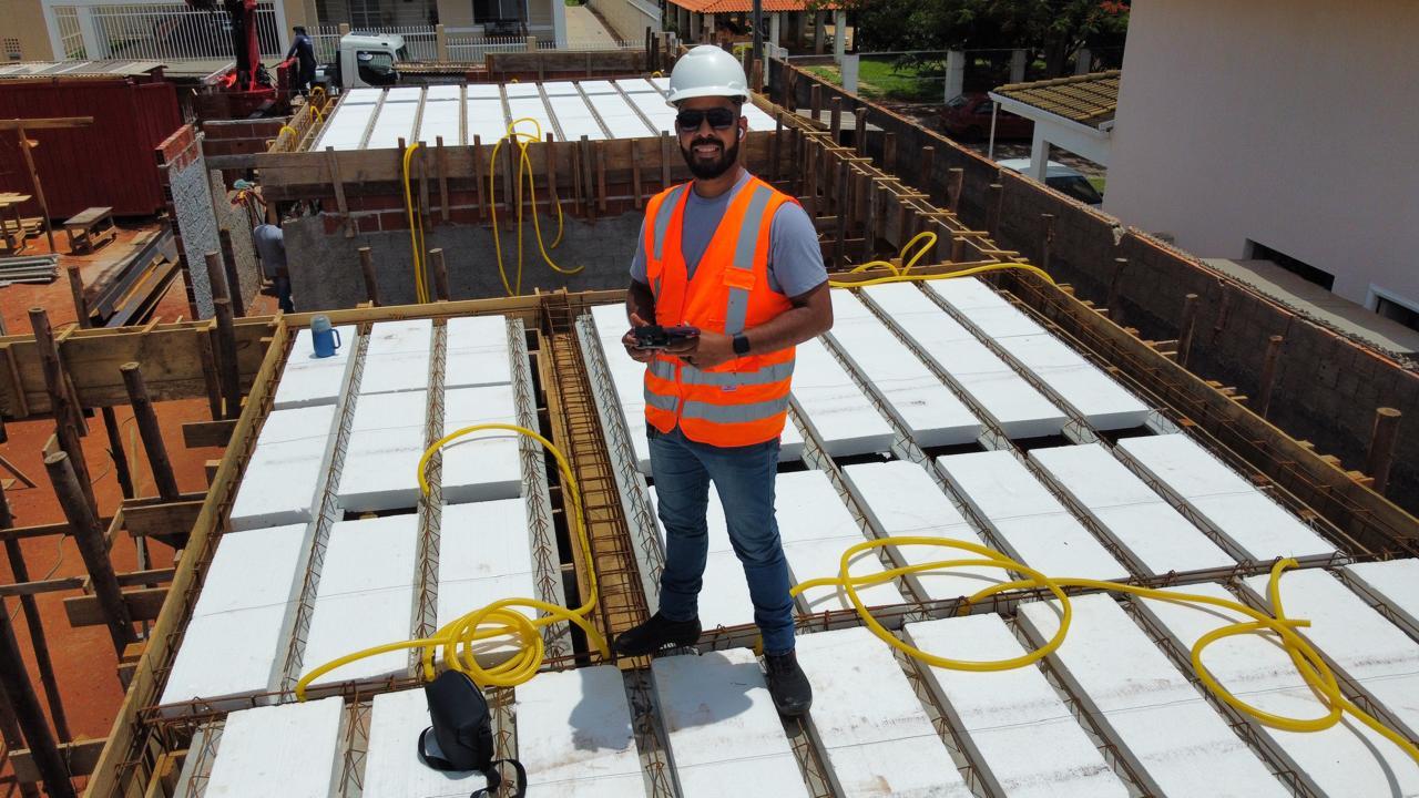 Engenheiro em laje durante execução de obra, com controle de drone